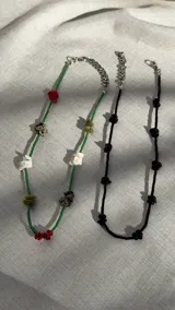 Choker de canutillos negros con detalles de escallas de piedra, con cierre de mosquetón y cadena de alargue metálica.