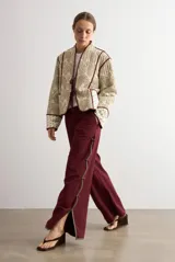 Pantalón ancho color bordó de talle alto, con abertura lateral decorada con ribete contrastante y cierre de botones tipo nudo chino.