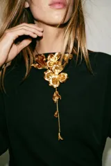 Collar doble de cadena metálica dorada con diseño de flores en relieve y hojas, con caída larga y detalles florales en los extremos.