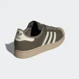 Championes Adidas Superstar II de diseño urbano, con parte superior de cuero nobuk en color verde oliva, franjas laterales y detalle en talón en color crema, y suela de goma en tono arena.