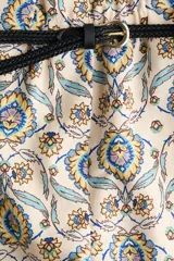 Short holgado de mezcla de lino, con estampado paisley en tonos beige, azul y amarillo, cintura elástica con pliegues, bolsillos laterales al bies y una franja azul con diseño floral en el ruedo. Incluye un cinturón trenzado fino con hebilla metálica.