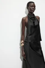 Top blanco satinado con cuello halter y escote fluido. Cierre en la espalda con botones.