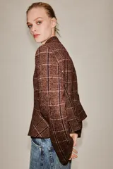Blazer de cuello subido y manga larga, con diseño peplum en el bajo y cierre frontal con botones. Confeccionado en tejido texturizado a cuadros.