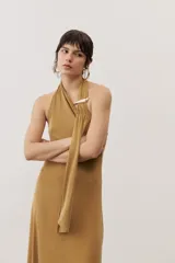 Vestido largo negro de corte al cuerpo con cuello halter y detalle de hebilla metálica dorada en el hombro con tira drapeada.