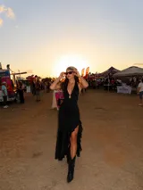 Vestido largo negro de corte ajustado, con escote halter profundo y detalle de abertura en el pecho. Presenta un tajo lateral con volados que recorren la abertura hasta el ruedo.