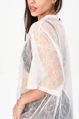 Remerón de encaje blanco transparente, de corte oversize, con mangas cortas y cuello redondo.