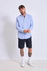 Camisa de corte regular con diseño de rayas verticales finas en tonos claros, cuello clásico y mangas largas con puños abotonados.