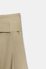 Falda midi color beige confeccionada en hilatura con mezcla de algodón. Presenta tiro medio, cintura con trabillas, bolsillos laterales ocultos en costura y cinturón del mismo tejido. Su diseño incluye un bajo acabado en línea evasé y cierre lateral con cremallera.