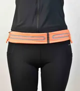 Riñonera deportiva color naranja con dos bolsillos con cierre y detalles reflectantes.
