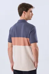 Remera polo de manga corta con diseño en bloques de color en tonos azul marino, blanco y verde militar, con bordado frontal y cierre de botones.