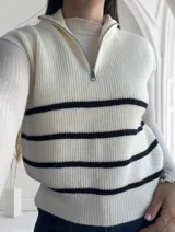 Chaleco de punto color crudo con rayas horizontales negras, cuello polo con cierre metálico y corte holgado.