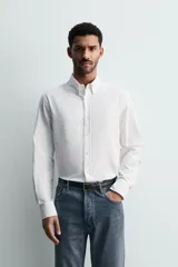 Camisa de corte regular fit confeccionada en tejido de algodón con efecto lavado. Presenta cuello abotonado, manga larga con puños abotonados, bolsillo en el pecho y cierre frontal con botones.