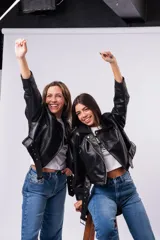 Campera biker de cuero sintético negro con cierre asimétrico, solapas anchas, bolsillos con cierre y cinturón ajustable en la cintura con hebilla metálica.