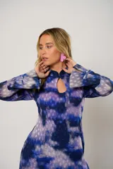 Vestido largo con estampado abstracto en tonos azul, lila y blanco. Tiene cuello mao con abertura en forma de lágrima, mangas largas acampanadas, espalda abierta, tajo frontal y flecos en el ruedo.