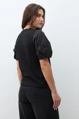 Remera negra de algodón con cuello redondo y mangas cortas abullonadas con detalle de frunces.