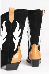 Bota estilo texana de gamuza color marrón, con diseño de apliques en forma de llamas en color crema y taco de madera.
