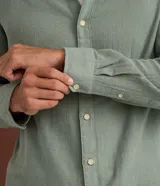 Camisa de manga larga para hombre de corte comfort, color verde, confeccionada en algodón con textura melange, cuello inglés y cierre frontal con botones.