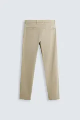 Pantalón chino de corte ajustado, color beige, con bolsillos laterales y bolsillos traseros de vivo. Cuenta con cierre frontal de cremallera y botón.