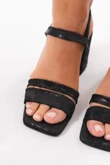 Sandalias de taco ancho color negro, con diseño de doble tira delantera, punta cuadrada y tira ajustable con hebilla en el tobillo.