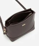 Cartera tipo hobo de tamaño pequeño, confeccionada en material sintético color marrón oscuro con acabado liso. Presenta una correa ajustable, cierre principal con cremallera y detalles metálicos dorados, incluyendo una placa con el logo de la marca en el frente.