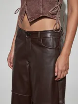 Bermuda estilo culotte confeccionada en cuerina color marrón chocolate, con diseño holgado y costuras horizontales decorativas en las piernas.