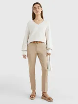 Pantalón chino color beige de sarga elástica, corte slim, con cierre de cremallera y botón, bolsillos traseros de ojal y logo de Tommy Hilfiger bordado en la parte trasera.