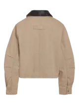 Chaqueta estilo worker de gabardina en color beige, con cuello camisero de cuerina negra, cierre frontal de cremallera y bolsillos frontales con cierre y ribete.