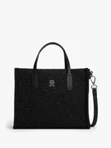 Cartera tipo tote de Tommy Hilfiger, color negro, confeccionada en nailon reciclado con diseño acolchado de monograma TH. Cuenta con dos asas superiores, correa ajustable extraíble, cierre de cremallera y logo metálico frontal.