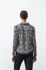 Camisa de manga larga color marrón con estampado de lunares blancos, confeccionada en tejido liviano con cuello clásico y botones frontales.