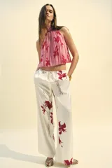 Top sin mangas color rosa con estampado de flores rojas, cuello halter y espalda descubierta.