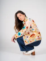 Chaqueta color crema con bordados florales de estilo suzani en tonos azules, rojos, amarillos y verdes.