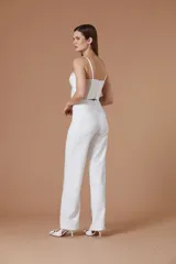 Pantalón de mujer blanco de corte sastrero, tiro alto y silueta amplia de pernera recta con detalles de flecos o pedrería en los laterales.