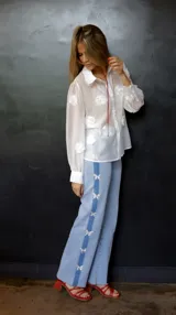 Pantalón de jean celeste con spandex y detalle de apliques de mariposas plateadas en los laterales. Corte recto y tiro medio.