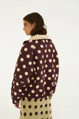 Campera reversible con estampado de lunares, cuello alto, cierre frontal y bolsillos laterales.