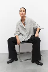 Pantalón de vestir negro de corte ancho y tiro alto, con elástico en la cintura y costuras verticales decorativas a lo largo de las piernas.