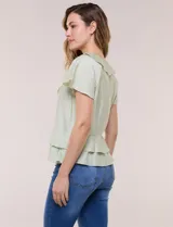 Blusa de satén texturizado color verde menta, con escote en V y volados que bordean el cuello. Presenta mangas cortas acampanadas y doble nivel de volados en la parte inferior, formando una silueta péplum.