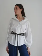 Cinturón negro con apliques de caballos plateados y argollas doradas. Se ajusta con un lazo en la parte posterior.