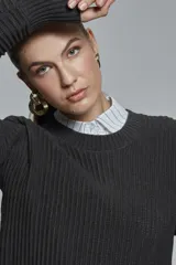 Sweater gris oscuro de tejido acanalado, corte relajado, cuello redondo y mangas largas con abertura.