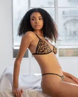 Conjunto de lencería de dos piezas con estampado animal print de leopardo, compuesto por un bralette triangular con tirantes regulables y detalles negros, y una colaless de tiras ajustables.