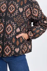 Campera puffer de abrigo con cierre frontal, cuello alto y puños elásticos. Presenta un diseño estampado con motivos geométricos y florales en tonos tierra sobre fondo negro.