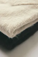 Chaleco de punto color beige claro con acabado afelpado o peludito, cuello en V y corte holgado.