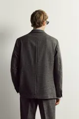 Blazer regular fit de Zara, confeccionada en tejido con mezcla de lana y lino en color gris oscuro con efecto jaspeado. Presenta cuello con solapas de muesca, manga larga con botones en los puños y un cierre frontal de un botón. Incluye bolsillos con solapa en la cadera, un bolsillo de vivo en el pecho y aberturas en la parte trasera.