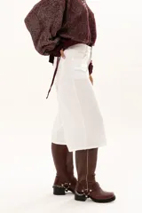 Bermuda de corte recto y tiro alto, confeccionada en gabardina blanca, con cierre frontal de botón y cremallera, y bolsillos laterales.