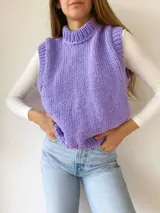 Chaleco tejido a mano color beige con cuello alto y sisas amplias.