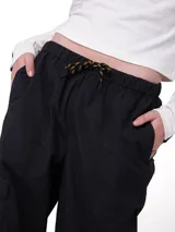 Pantalon cargo de corte relajado color negro, confeccionado en nylon. Presenta cintura elástica con cordón ajustable, bolsillos laterales y un bolsillo cargo con etiqueta de la marca en el lateral derecho.