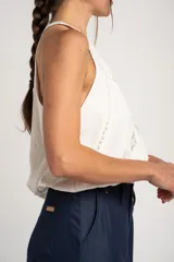 Top de viscosa y poliamida color blanco, con cuello halter y detalles de inserciones de encaje transparente formando una equis en el frente.