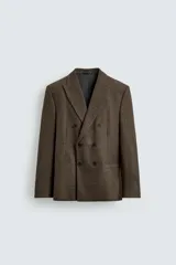 Blazer de corte relajado confeccionada en tejido con lana, con diseño de cuadros pequeños. Presenta cuello con solapas de pico, cierre frontal de botonadura cruzada, manga larga con botones en los puños y bolsillos de vivo en el pecho y la cadera.