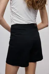 Short cruzado de tiro medio con diseño frontal tipo falda, color negro, de líneas simples y calce cómodo.