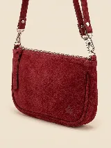 Cartera tipo bandolera de gamuza color bordó, con diseño rectangular de bordes redondeados, cierre superior metálico y correa ajustable con herrajes plateados. Presenta un pequeño logo grabado en relieve en la parte inferior.