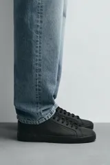 Zapatillas de cordones de estilo minimalista, color negro, con diseño liso, horma redonda, forro interior en tono contrastante y suela de goma texturizada.